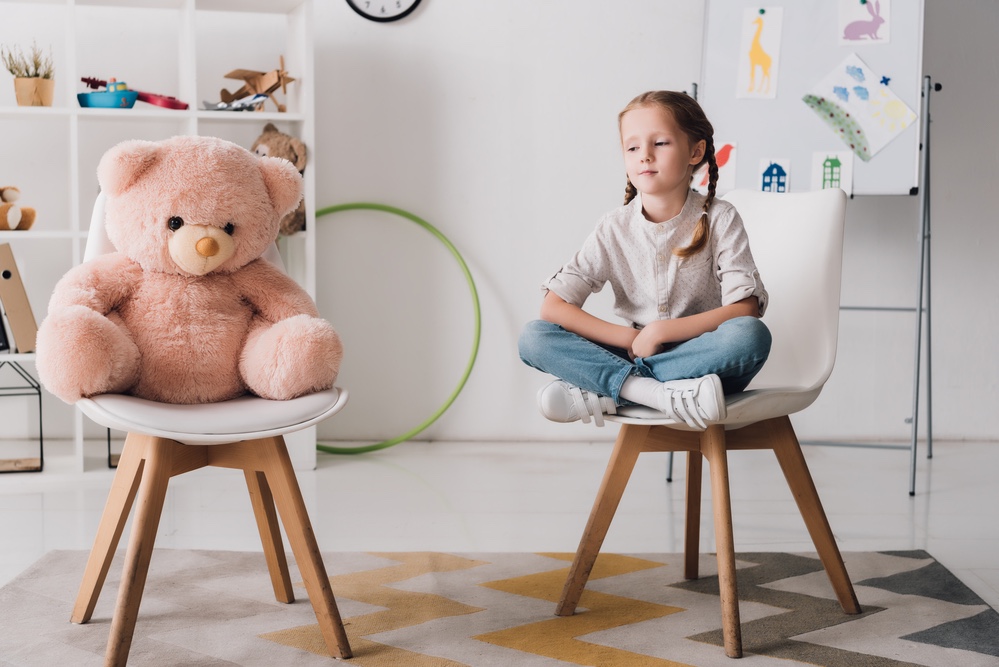 Lonely little girl with teddy bear.