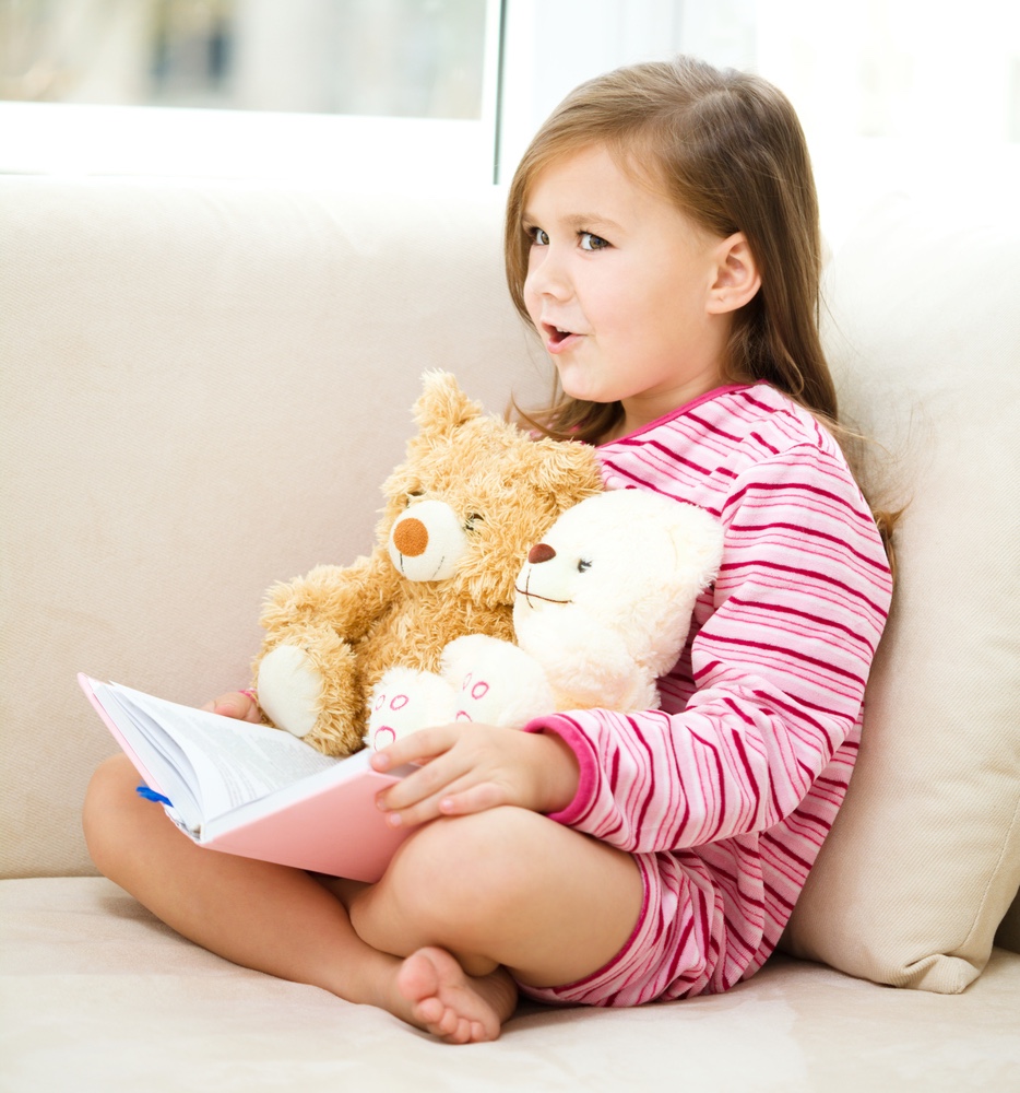 Little Girl reading to teddy bear