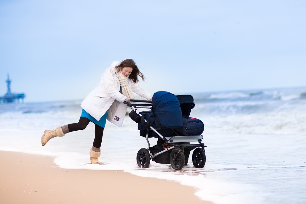 Mom walking with her baby in a stroller on beach