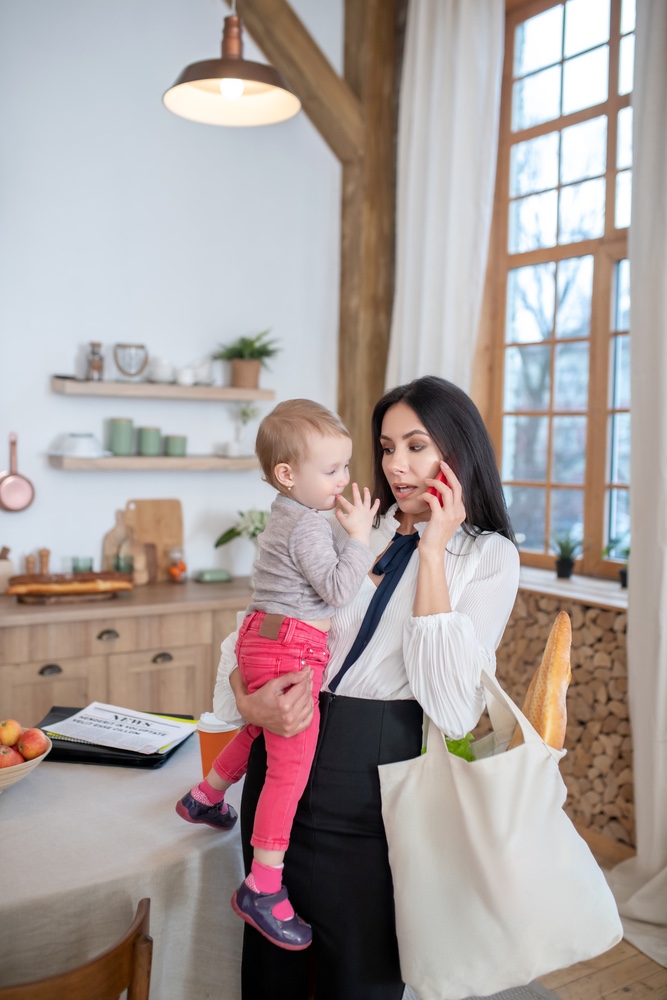 Multitasking mom with groceries, phone and child