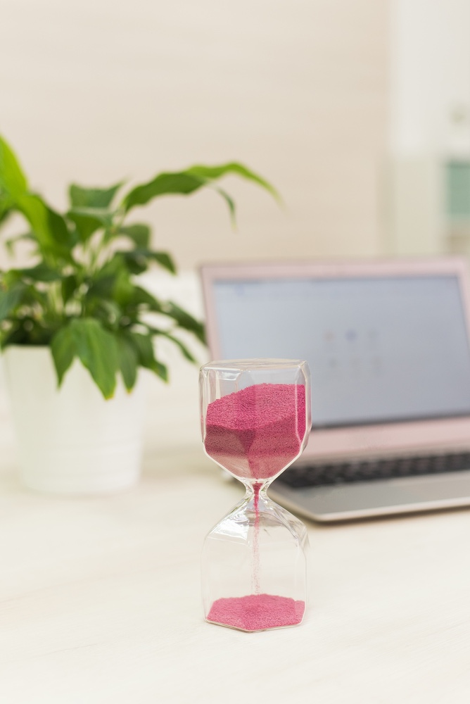 Hour glass next to laptop. Valuing your time.