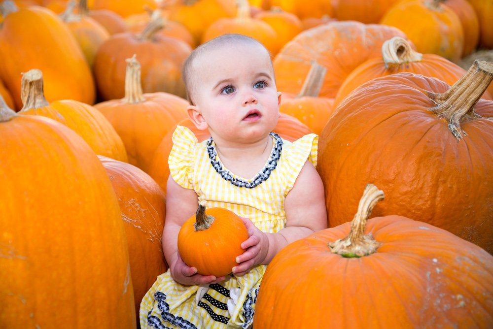 Baby in pumpkin patch for baby’s 1st Halloween