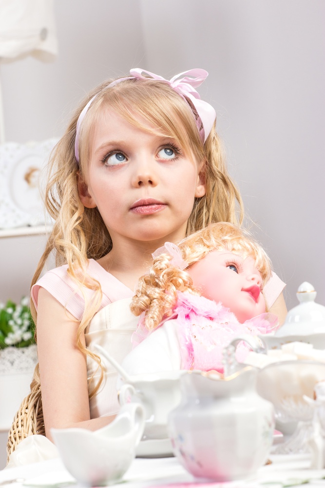 Little girl having tea party with doll