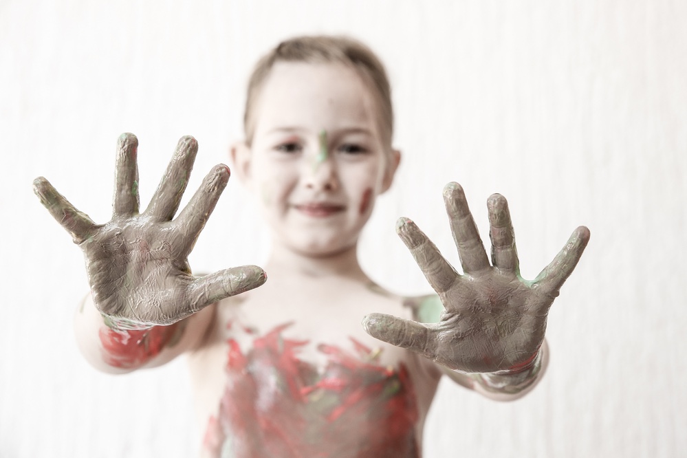 Happy girl with paint on her hands. Messy play.